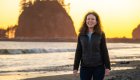 Woman smiling at sunset on the beach of Washington’s Olympic Peninsula, a scenic stop on an Olympic National Park e-biking adventure.