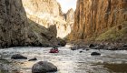 A raft floating down the Owyhee river with scenic cliffs surrounding the river.