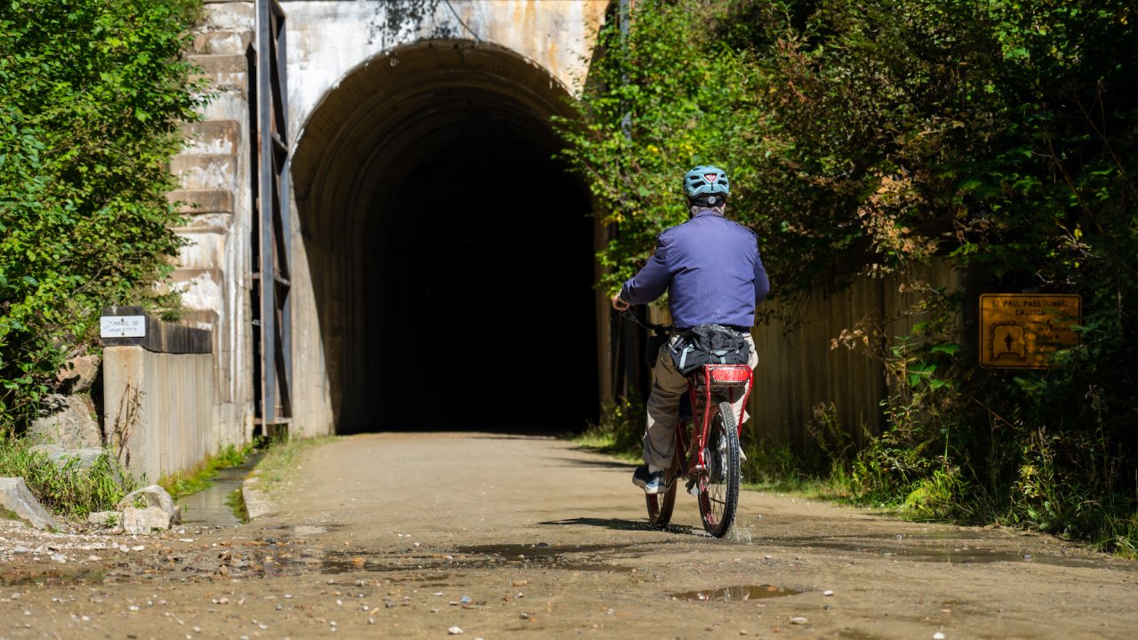 A person biking into a tunnel on a sunny day