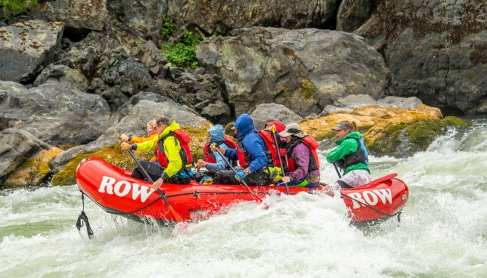 people in red whitewater raft in jackets and hats