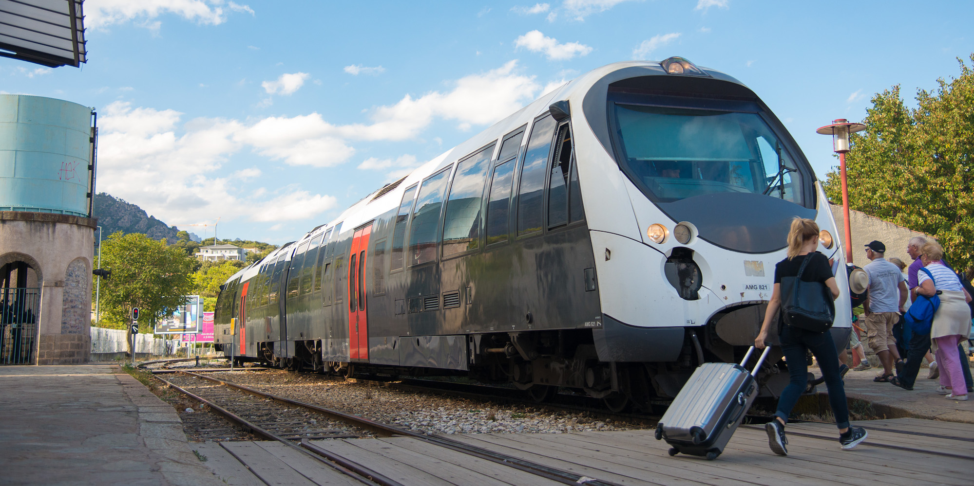 Train stopped at a train stop while people carrying luggage board in France