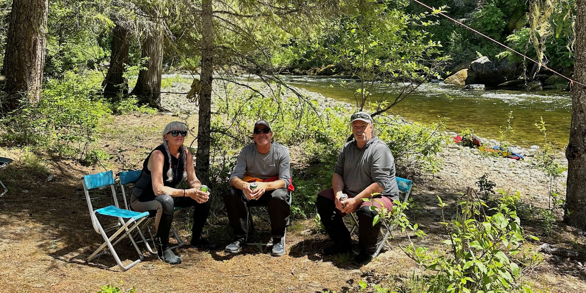 Three people lounging by an Idaho river on a sunny day.