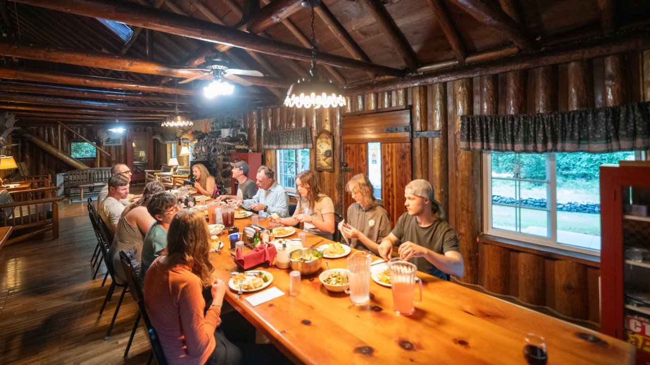 A group of hikers having a meal inside of a Rogue River lodge after a day of hiking.