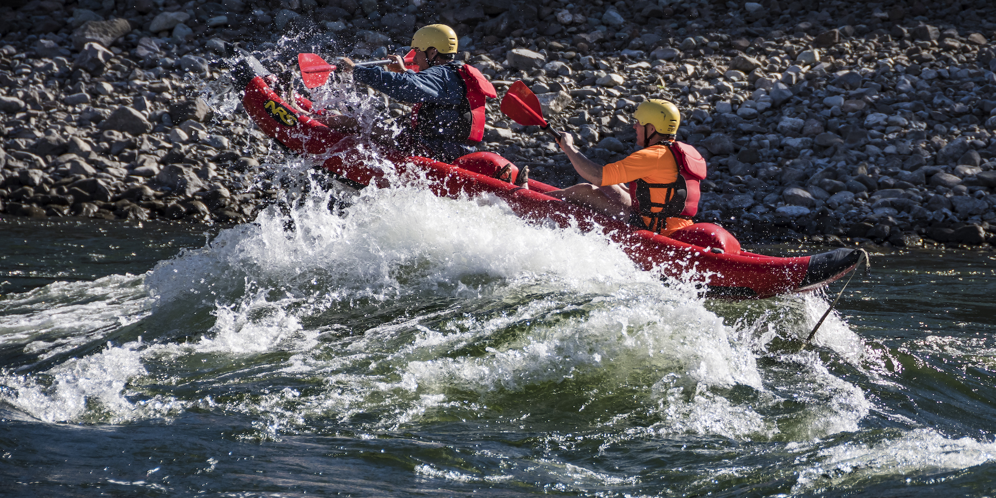 A tandem inflatable kayak rolling over waves