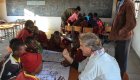 A tourist sitting around a table with kids from Africa in their classroom
