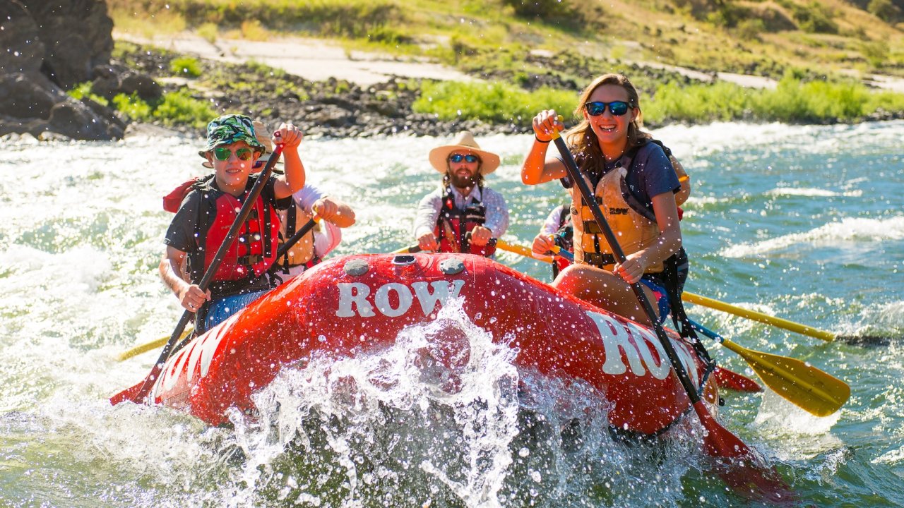 A red raft floating downstream through a splashy rapid on the Salmon rier