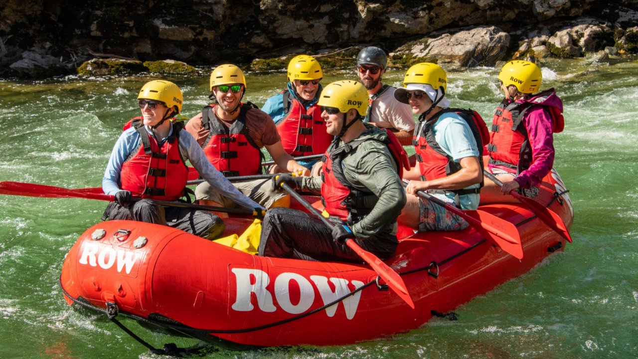 red whitewater raft with people floating in green water