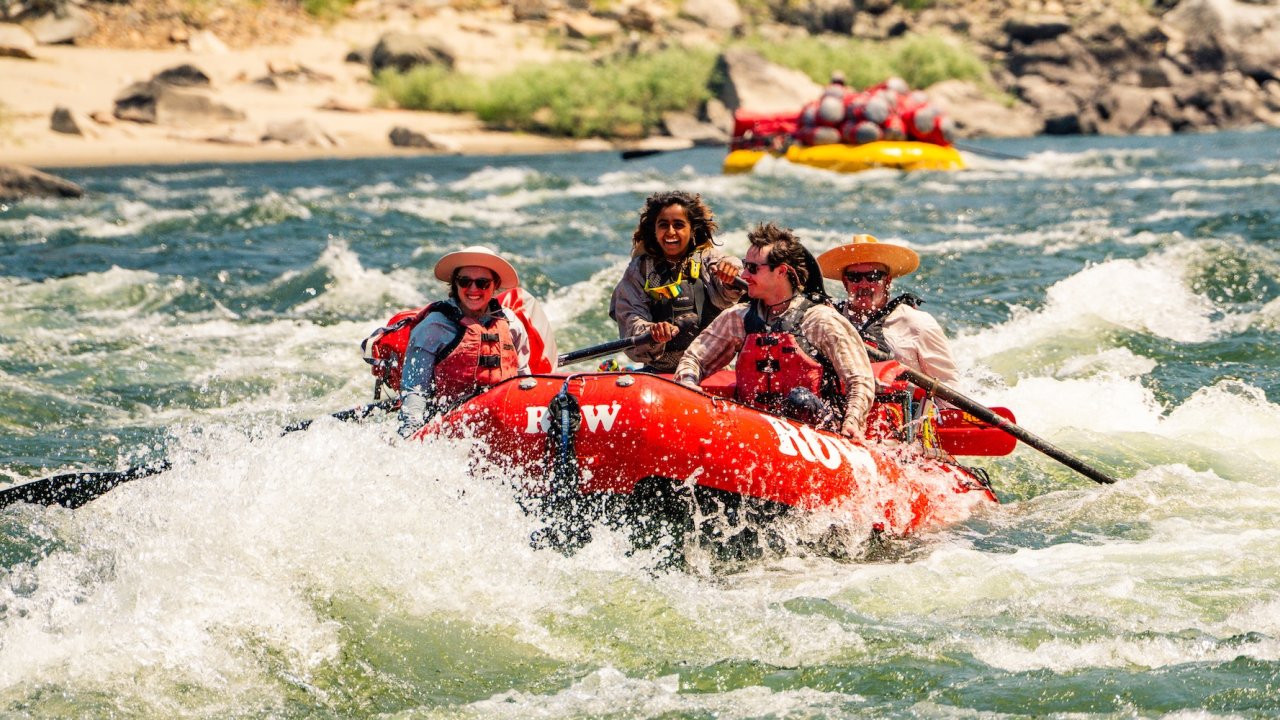 Smiling group rafting through rapids on a salmon river white water rafting Idaho adventure.