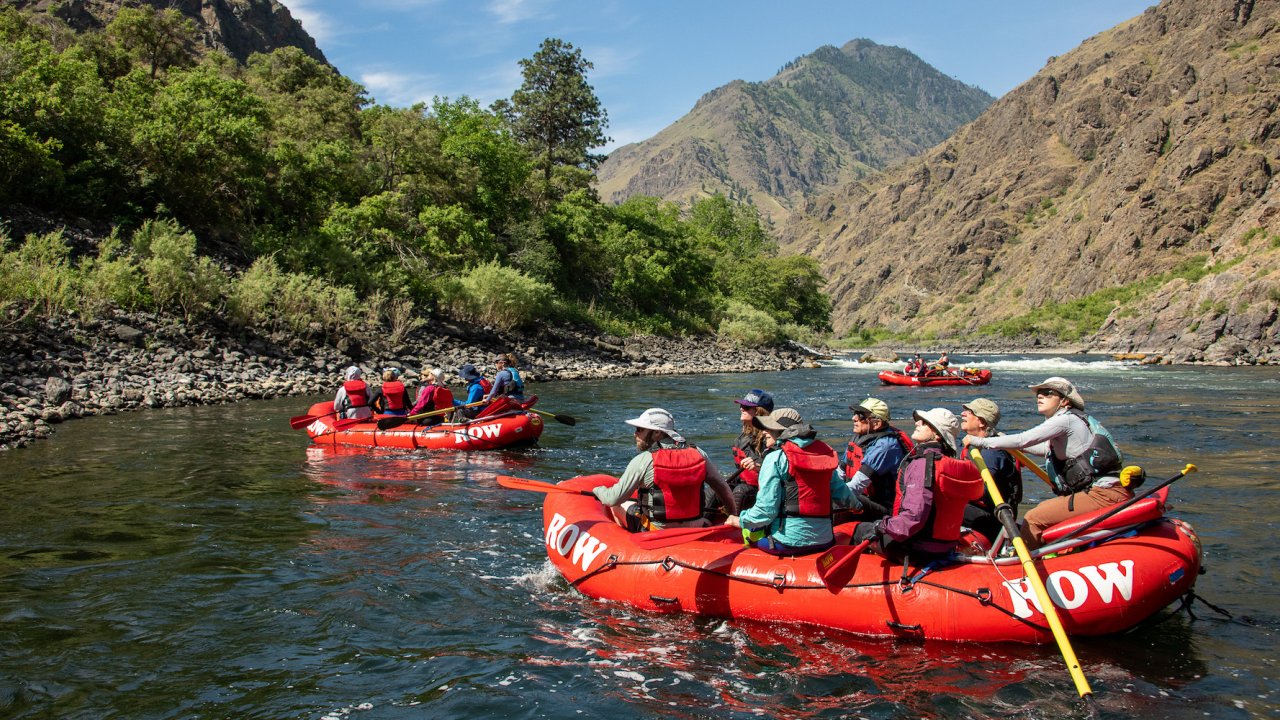 Red whitewater rafts on the Snake River in the sun all admiring the deepest river gorge in North America