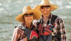 A couple in sun hats smiling on the river in Northern Idaho