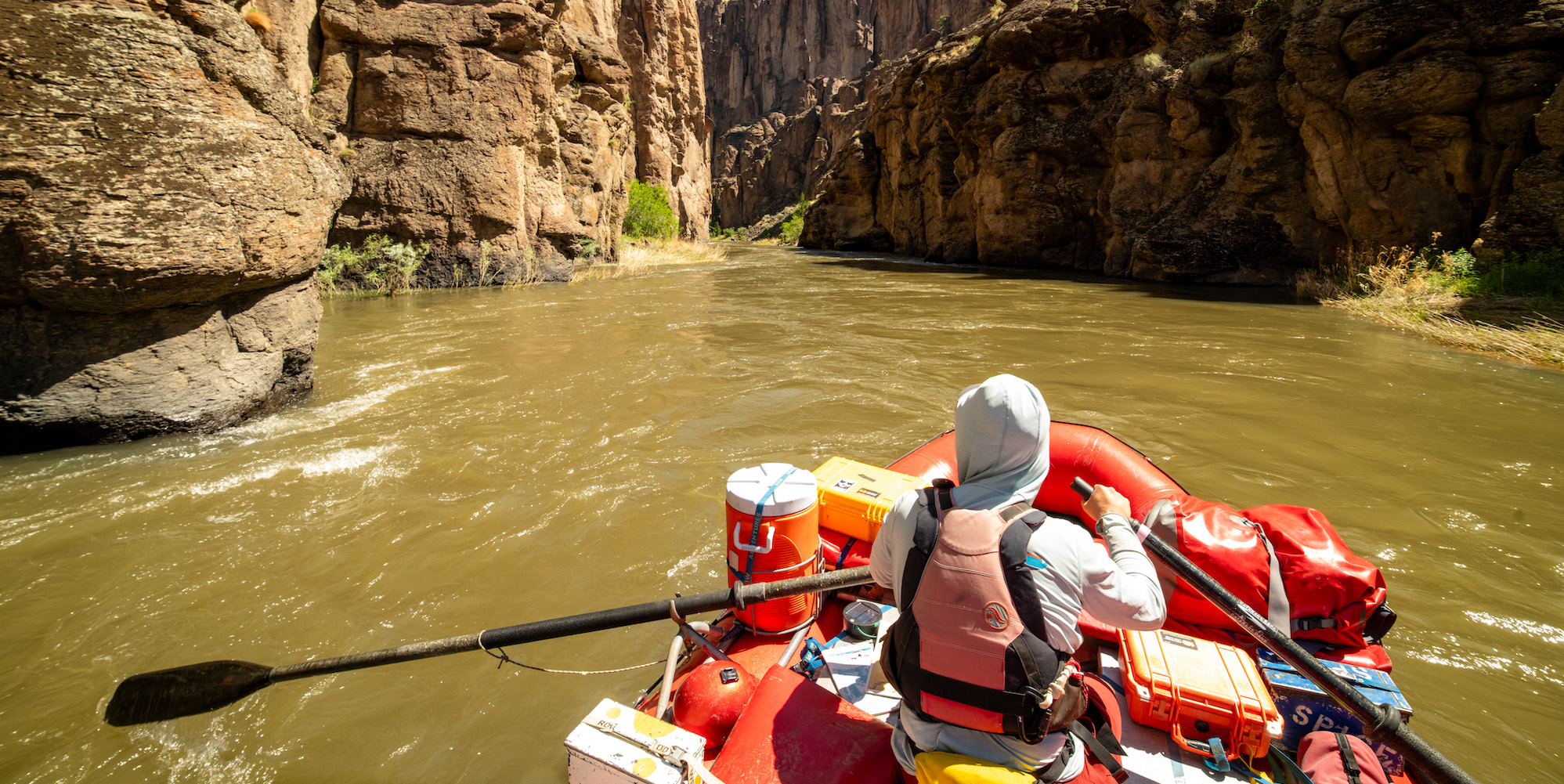 ROW Adventures guide wearing a sun hoodie underneath his PFD while rowing down the Bruneau River