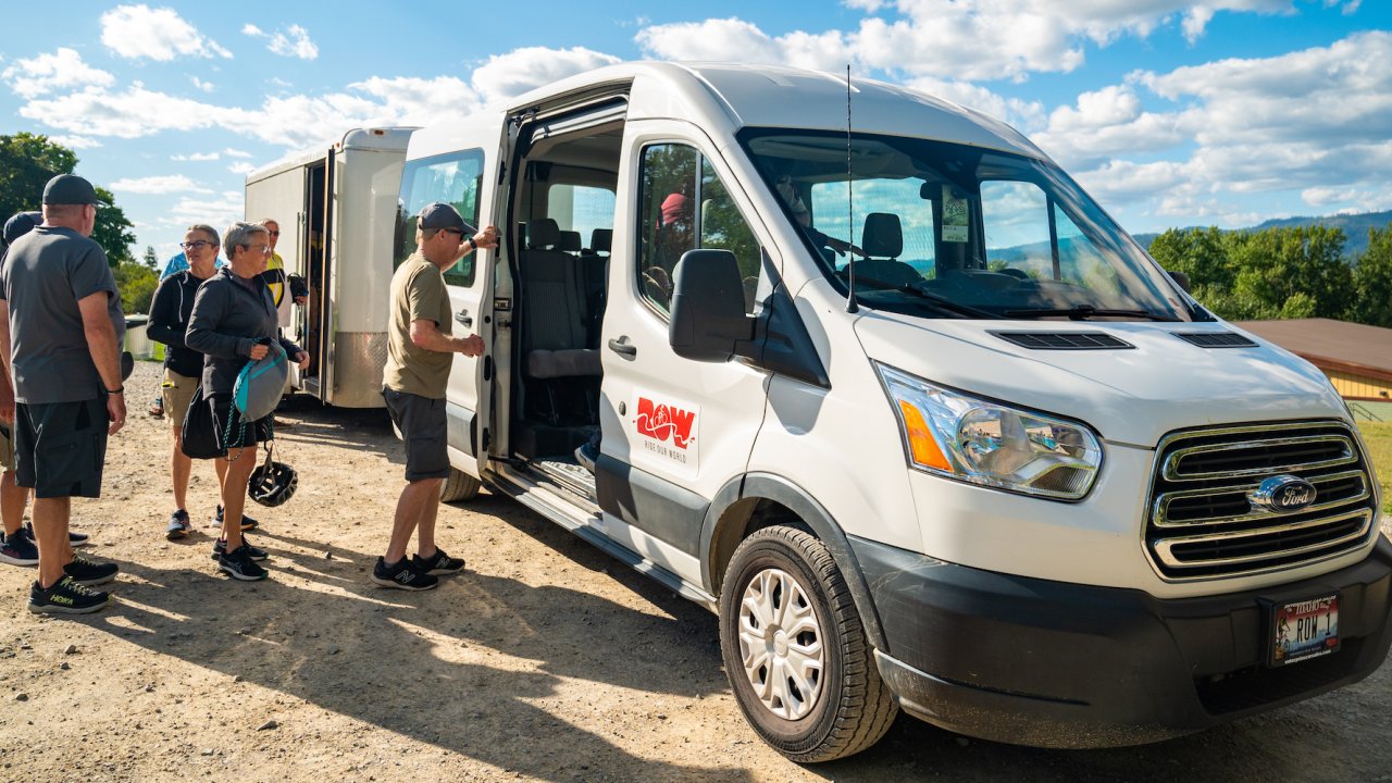 Guests filing into a white ROW Adventures branded van on a group bike tour
