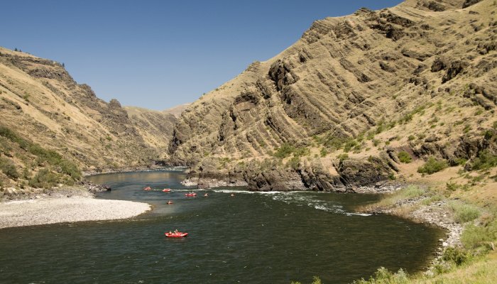 Red ROW rafts float down the Salmon River Canyons on a sunny summer day