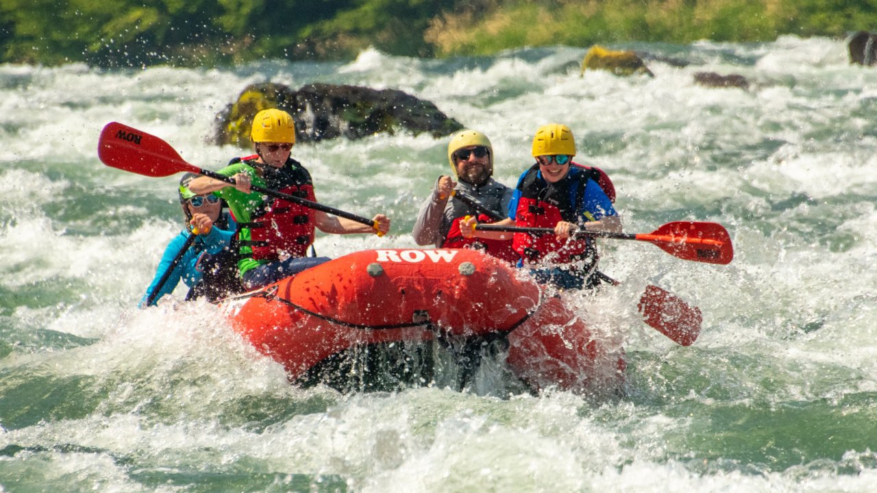 Red raft full of passengers paddling through a rapid on the Deschutes River