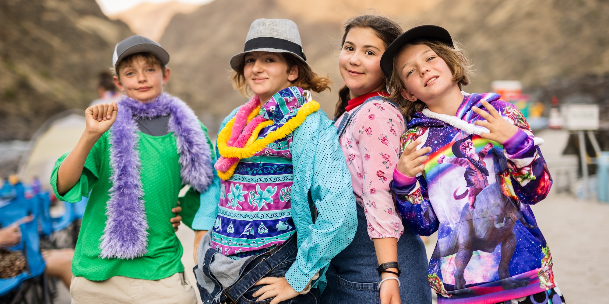 A group of kids on a beach dressed up in colorful clothing.