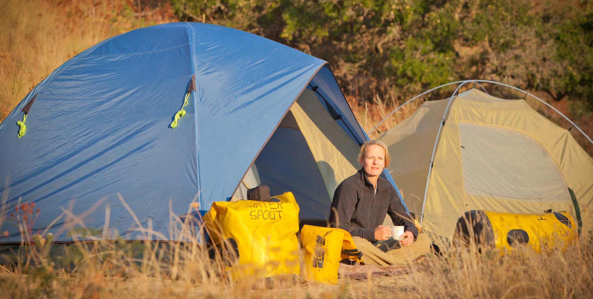 Woman sitting outside of her tent while camping along the Snake River