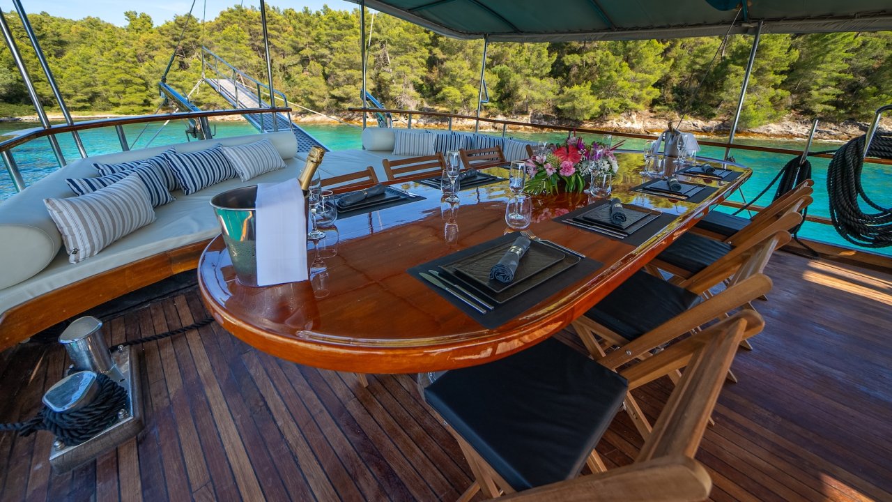 An outdoor dining area on a yacht in Croatia with a table set for a meal.