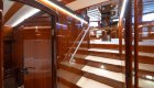 A glossy wooden staircase inside a yacht leading to the main deck.