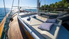 A sun deck on a yacht with cushioned lounge chairs, striped pillows, and ocean views.