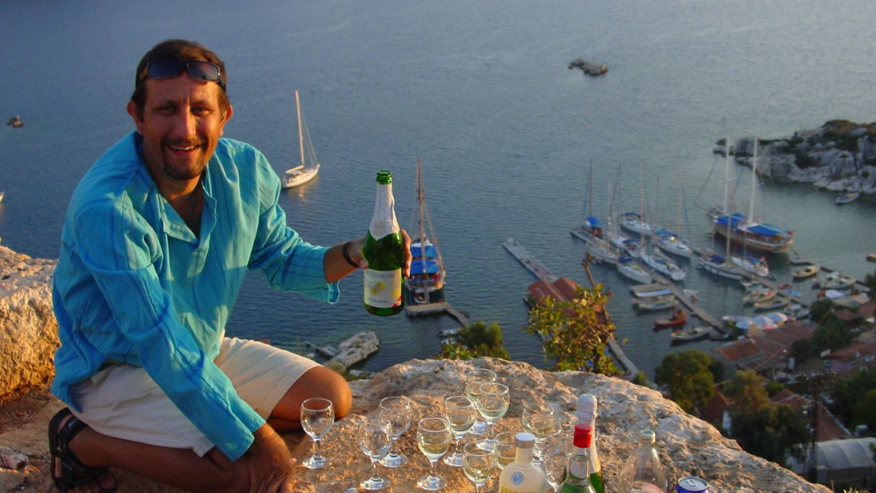 Tour guide in Turkey sitting at an ocean overlook pouring a glass of wine and smiling